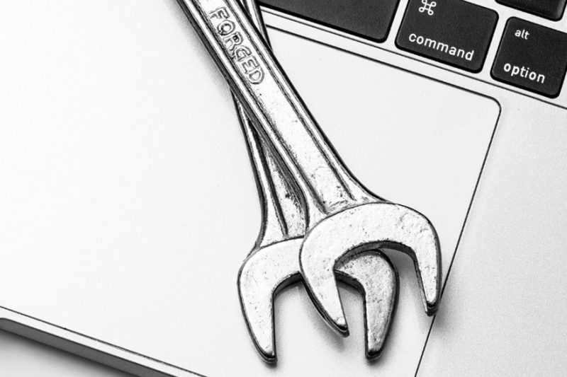 Image of a laptop with two wrenches on top, signifying computer repair and consultation.